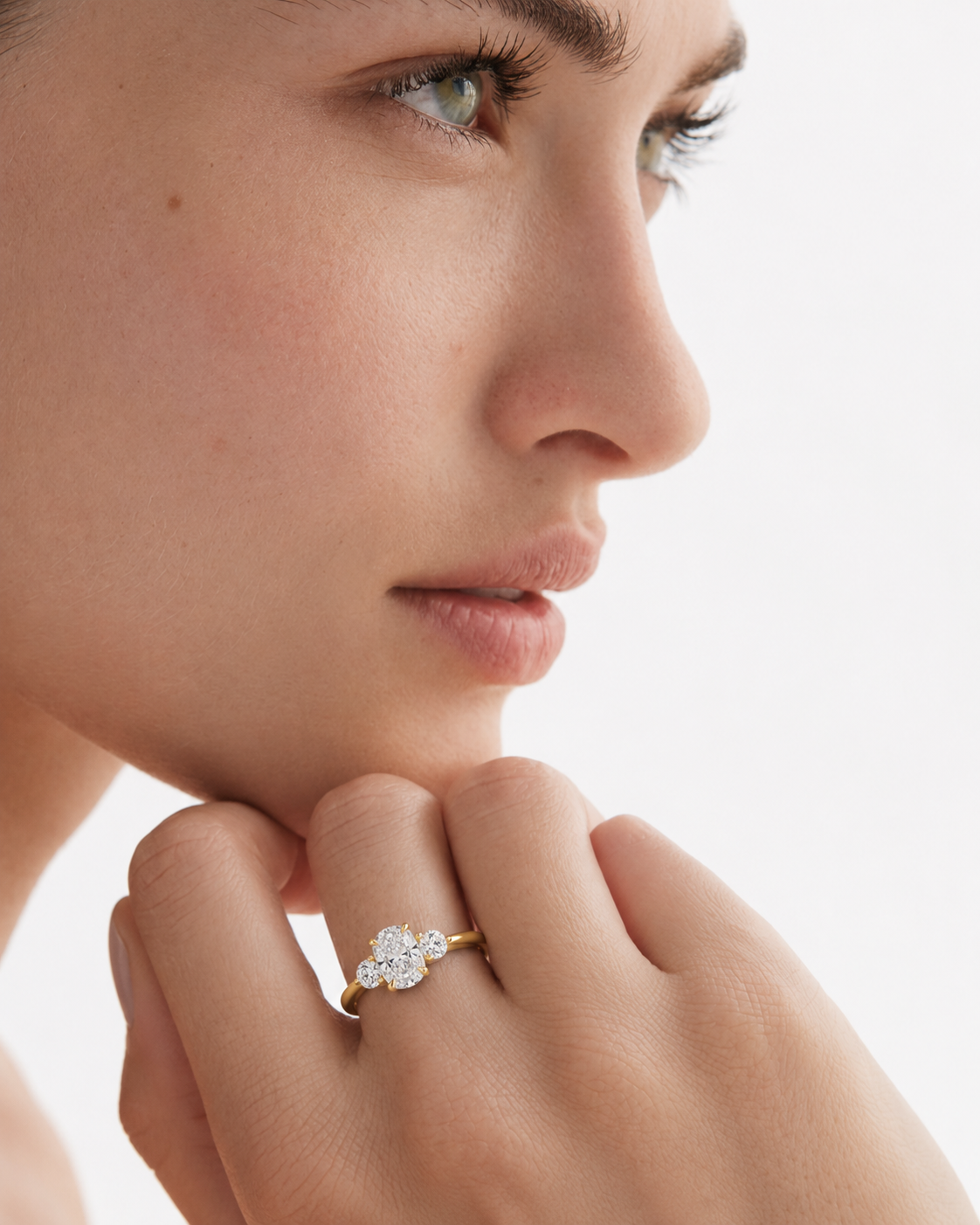 color_10K_YG, color_14K_YG &&A close-up lifestyle shot of a model wearing a delicate gold ring with a small cluster of clear gemstones on her finger, set against a clean, bright white background.