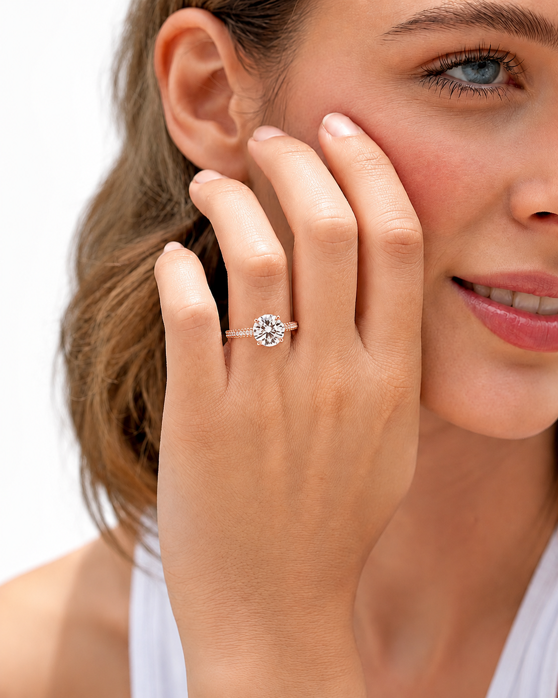 color_10K_RG, color_14K_RG &&A close-up lifestyle shot of a woman wearing a silver-toned solitaire engagement ring with a round-cut clear gemstone on her finger.
