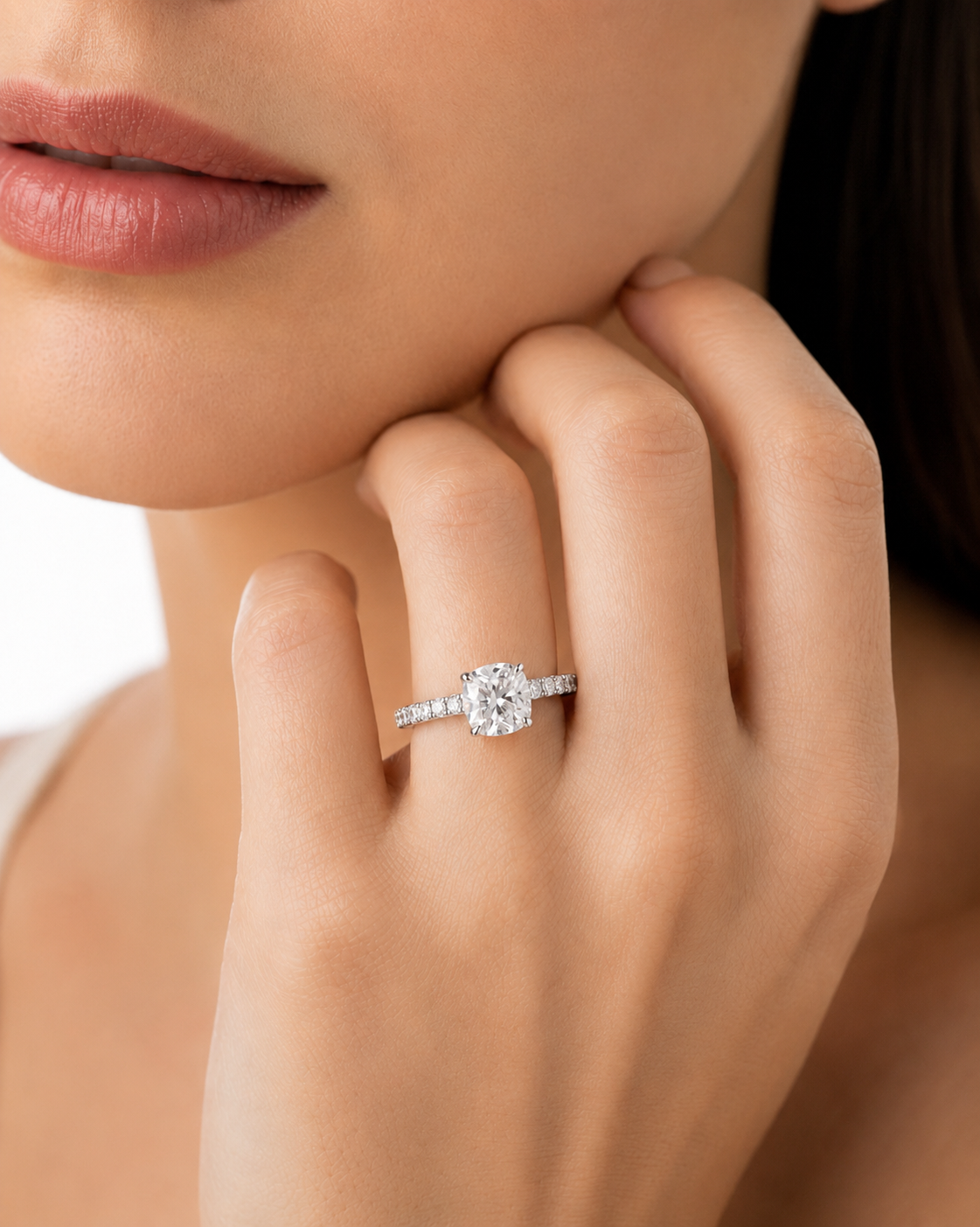 color_925_SIL,color_935_ARG,color_10K_WG, color_14K_WG &&A close-up lifestyle shot of a woman wearing a radiant-cut diamond engagement ring on a silver band, with her hand resting near her chin.