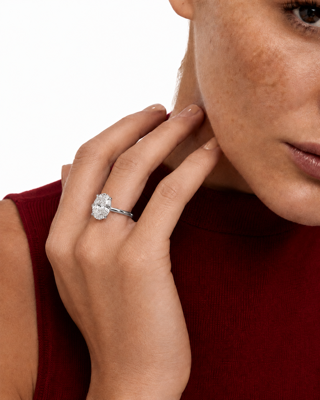 color_925_SIL,color_935_ARG,color_10K_WG, color_14K_WG &&A close-up lifestyle shot of a woman wearing a silver-toned diamond engagement ring on her finger, wearing a dark red ribbed top against a clean white background.