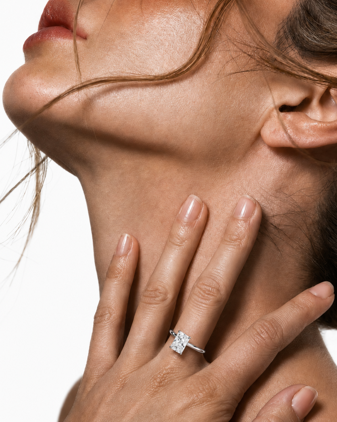 color_925_SIL,color_935_ARG,color_10K_WG, color_14K_WG &&A close-up lifestyle shot of a woman's neck and hand, wearing a delicate gold ring with a clear central gemstone on her finger against a white background.