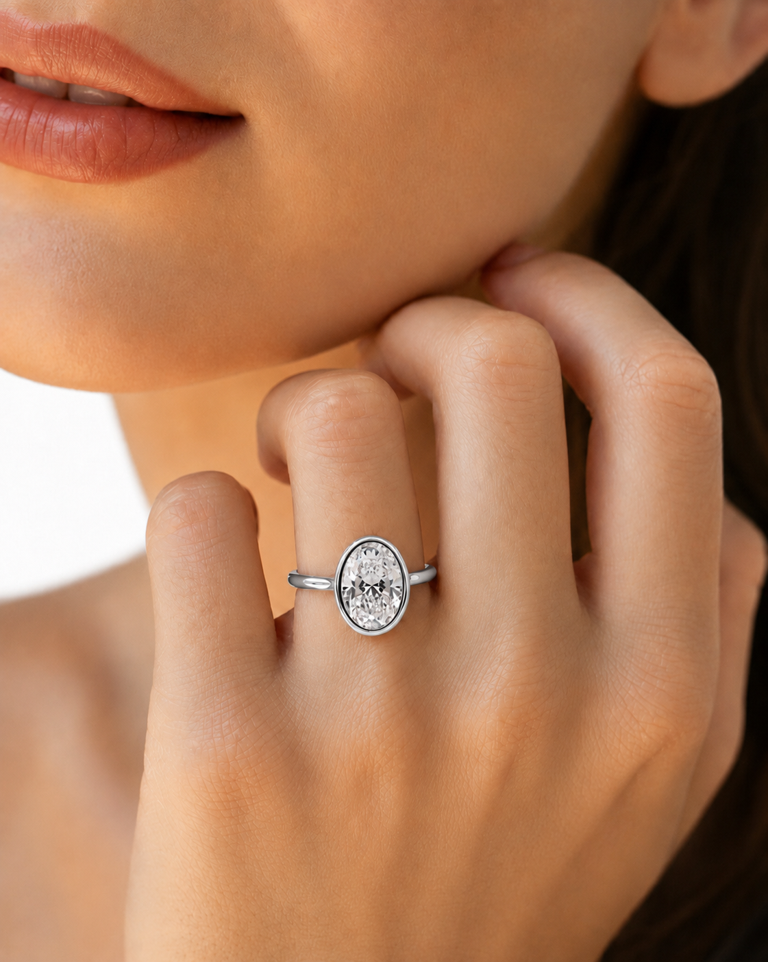 color_925_SIL,color_935_ARG,color_10K_WG, color_14K_WG &&A close-up lifestyle shot of a model wearing a silver oval ring with a clear, textured central stone on her finger.