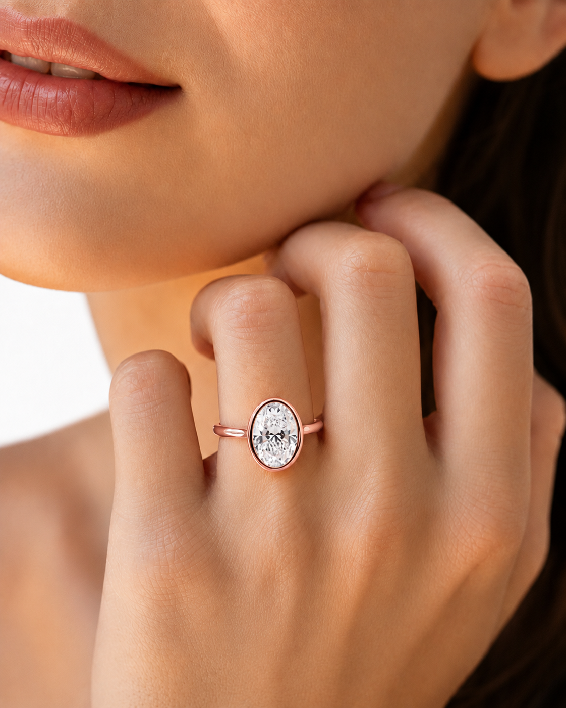 color_10K_RG, color_14K_RG &&A close-up lifestyle shot of a model wearing a delicate rose gold oval ring with a clear crystal center on her finger.