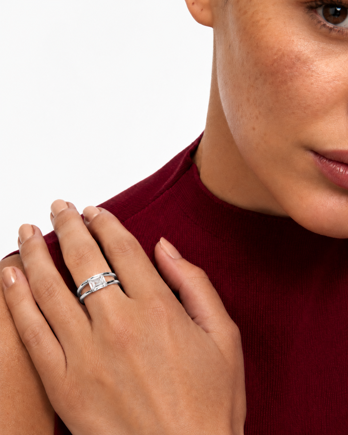 color_925_SIL,color_935_ARG,color_10K_WG, color_14K_WG &&A close-up of a woman wearing a silver double-band ring with clear stones, resting her hand on her shoulder. She is wearing a dark red ribbed top against a clean white background.