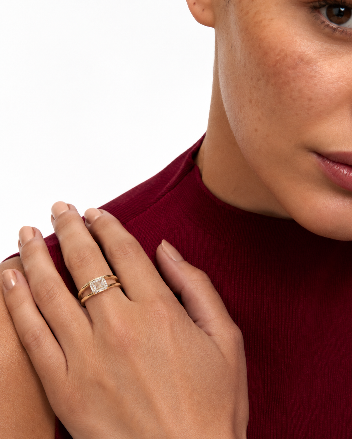 color_10K_YG, color_14K_YG &&A close-up of a model's hand wearing a rose gold ring with a square-cut clear gemstone, set against a clean white background and a dark red ribbed top.