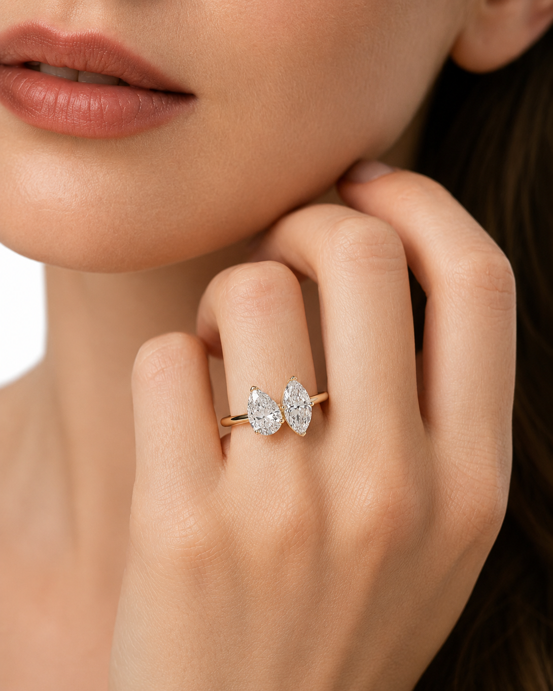 color_10K_YG, color_14K_YG &&A close-up lifestyle shot of a model wearing a delicate gold ring with two pear-cut clear gemstones in a butterfly-like setting.