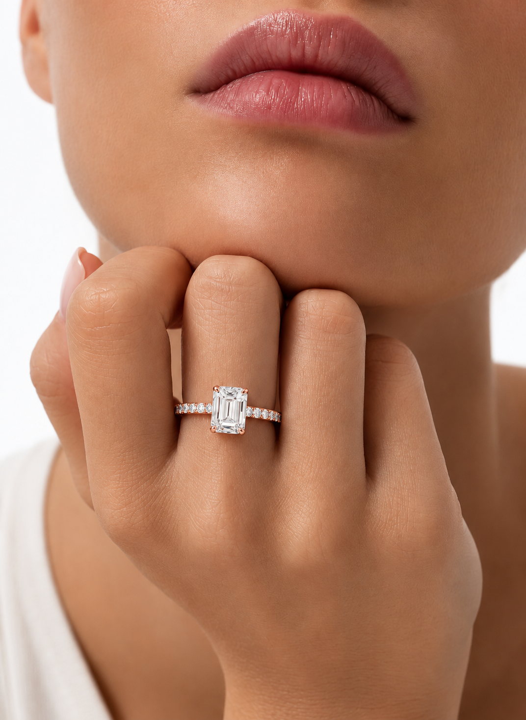 color_10K_RG, color_14K_RG &&A close-up lifestyle shot of a model wearing a silver engagement ring with a large emerald-cut center stone and small side stones.
