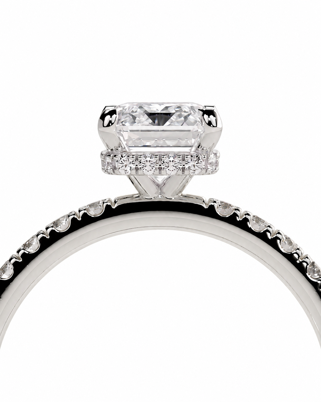 color_925_SIL,color_935_ARG,color_10K_WG, color_14K_WG &&A close-up studio shot of a diamond ring featuring a large rectangular emerald-cut center stone and a halo of smaller diamonds, set on a polished silver-toned band with pave diamonds along the shoulders, against a plain white background.