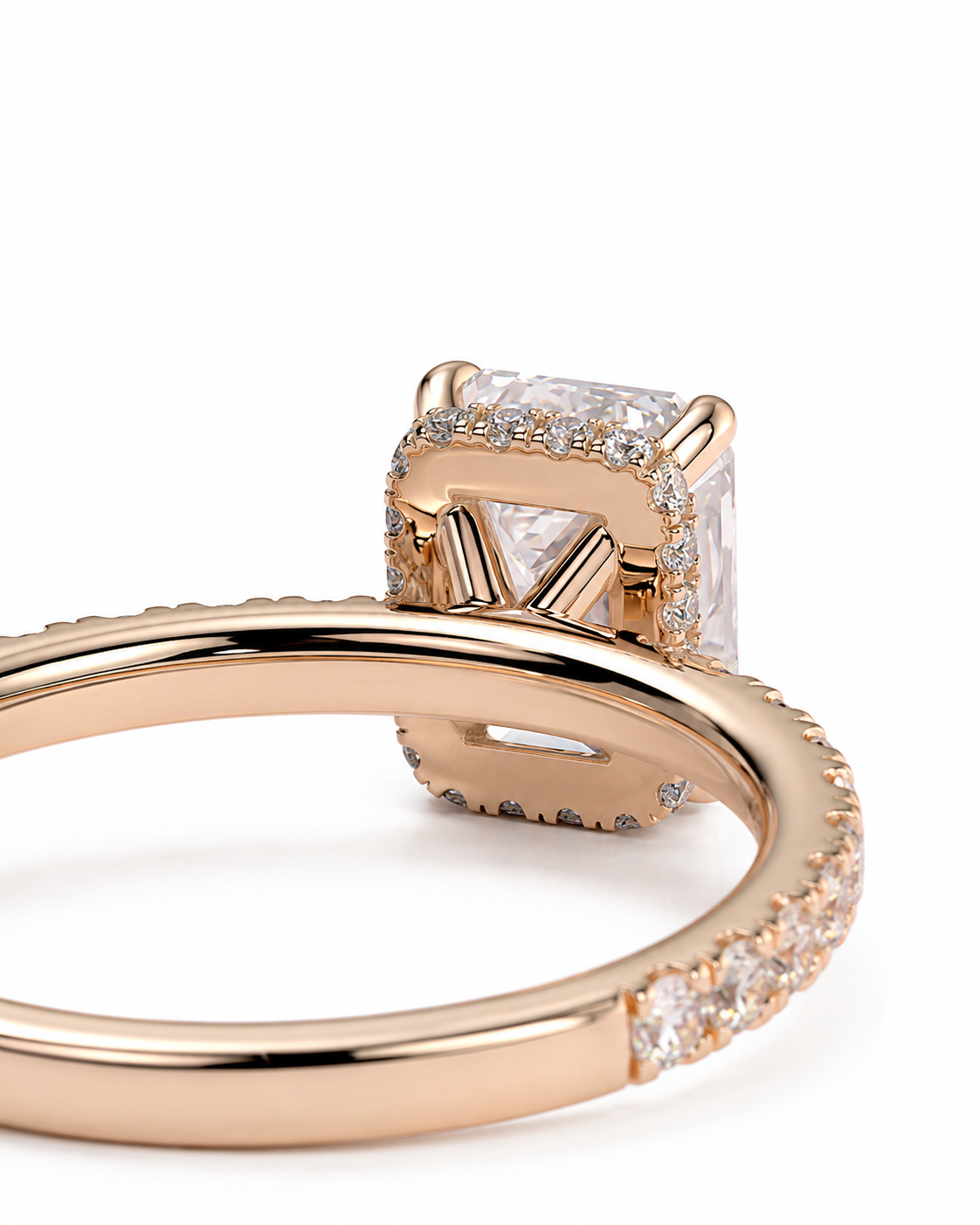 color_10K_RG, color_14K_RG &&A close-up studio shot of a rose gold ring featuring a large rectangular clear gemstone in a halo setting, with a pave band on a white background.