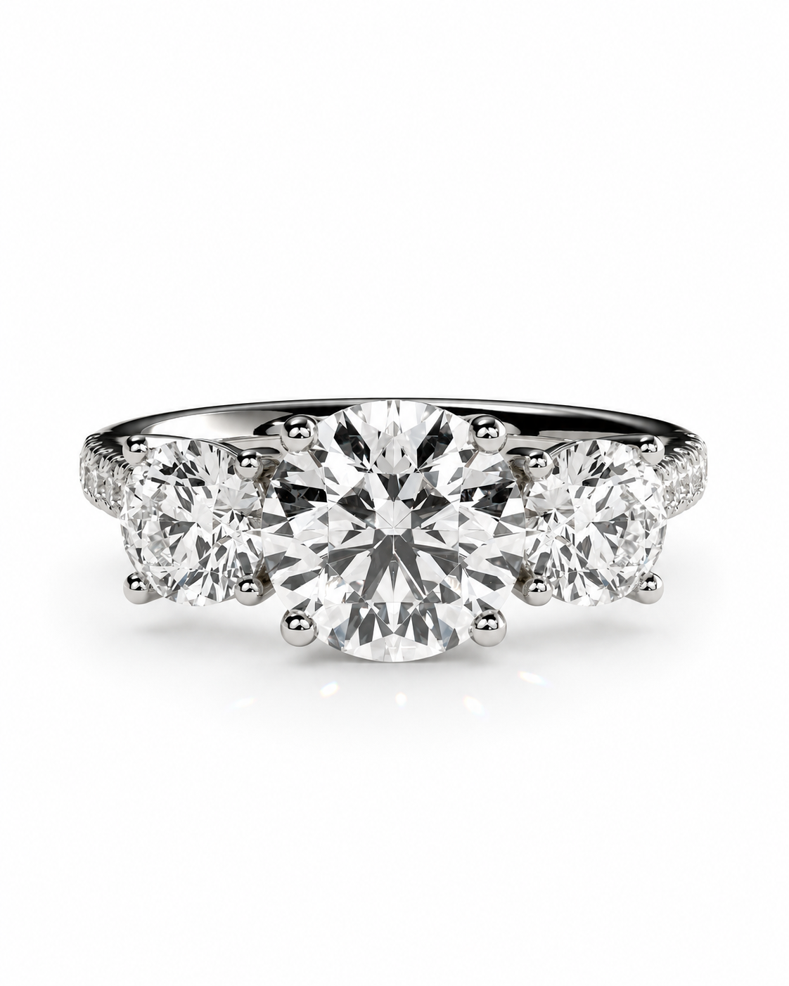 color_925_SIL,color_935_ARG,color_10K_WG, color_14K_WG &&A three-stone diamond engagement ring with a round center stone and two round side stones, set in a polished silver-colored metal band on a white background.
