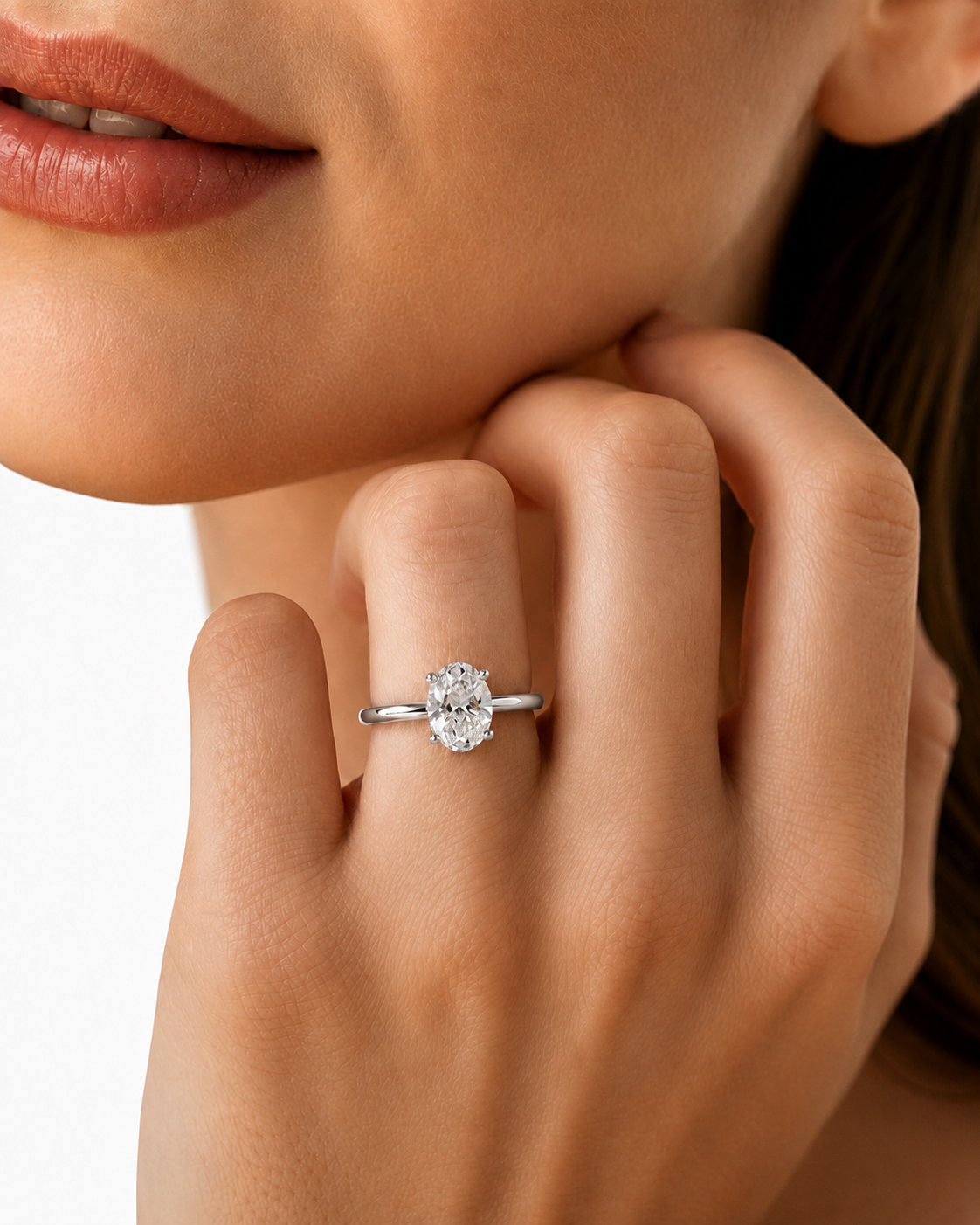 color_925_SIL,color_935_ARG,color_10K_WG, color_14K_WG &&A close-up lifestyle shot of a woman wearing a silver engagement ring with a round-cut clear gemstone on her finger.
