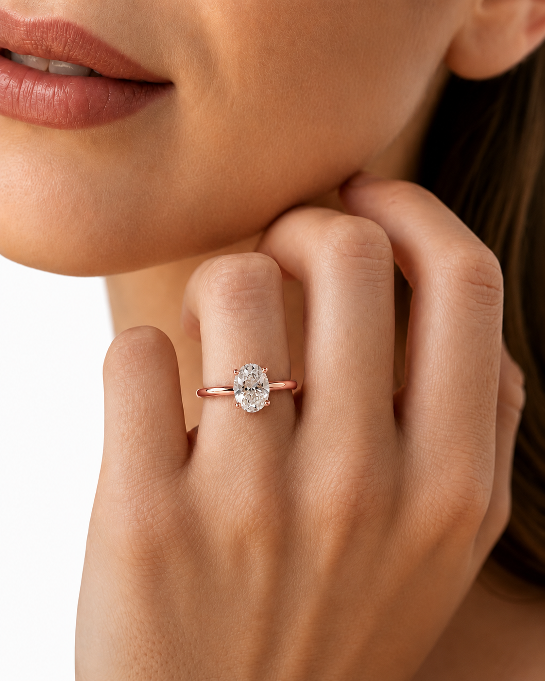 color_10K_RG, color_14K_RG &&A close-up lifestyle shot of a woman wearing a delicate rose gold ring with a round-cut clear gemstone on her finger, set against a clean white background.