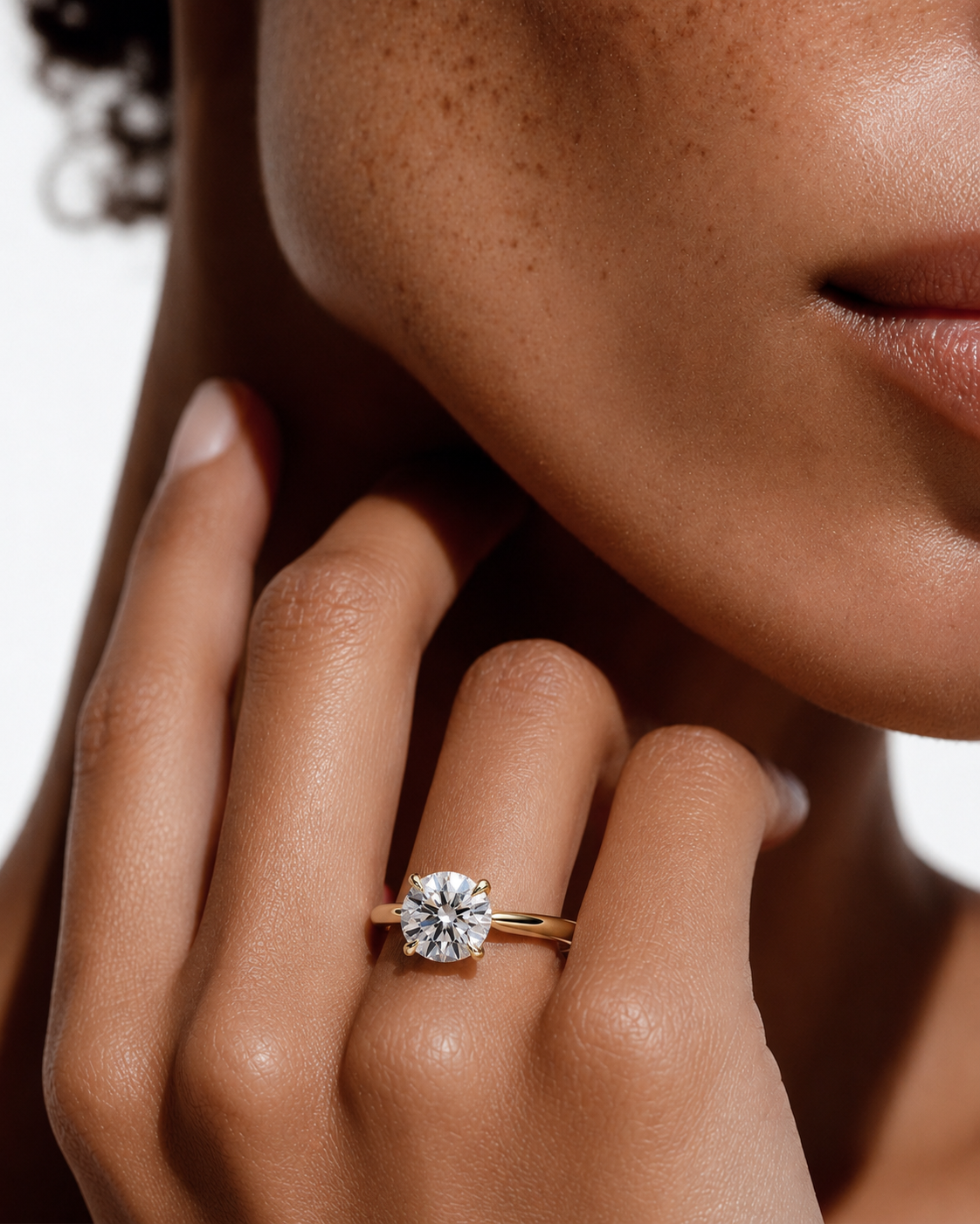 color_10K_YG, color_14K_YG &&A close-up lifestyle shot of a model wearing a classic solitaire engagement ring. The ring features a round brilliant-cut diamond set in a yellow gold band, shown on the model's ring finger against a clean white background.
