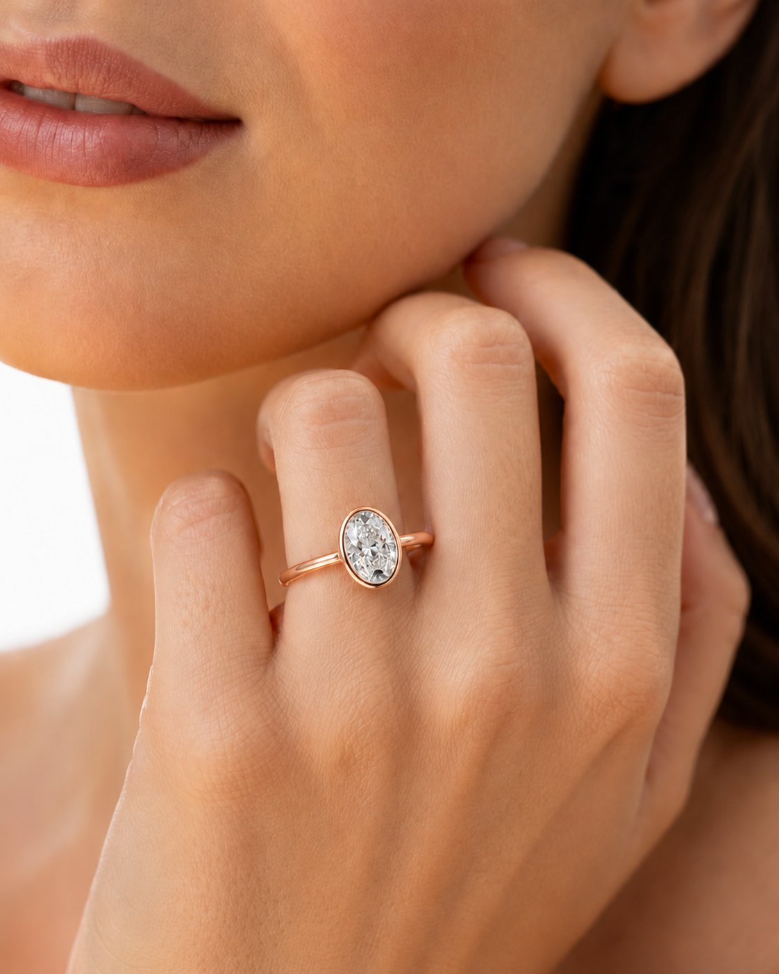 color_10K_RG, color_14K_RG &&A close-up lifestyle shot of a model wearing a rose gold ring with an oval, textured clear gemstone on her finger.