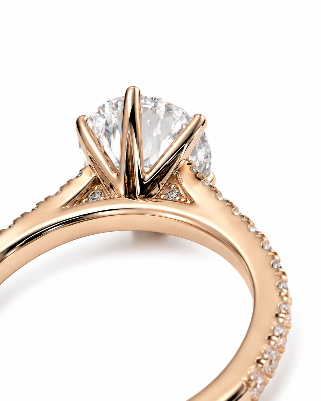 color_10K_RG, color_14K_RG &&Close-up of a rose gold engagement ring featuring a round brilliant-cut diamond center stone in a four-prong setting, with small pavé diamonds along the shank, on a white background.