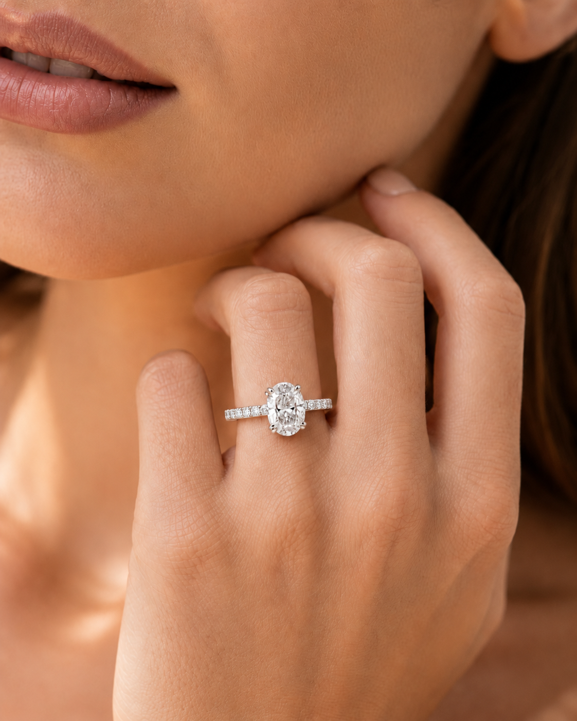 color_925_SIL,color_935_ARG,color_10K_WG, color_14K_WG &&A close-up lifestyle shot of a woman wearing a silver ring with a round-cut center stone and small side stones on her finger.