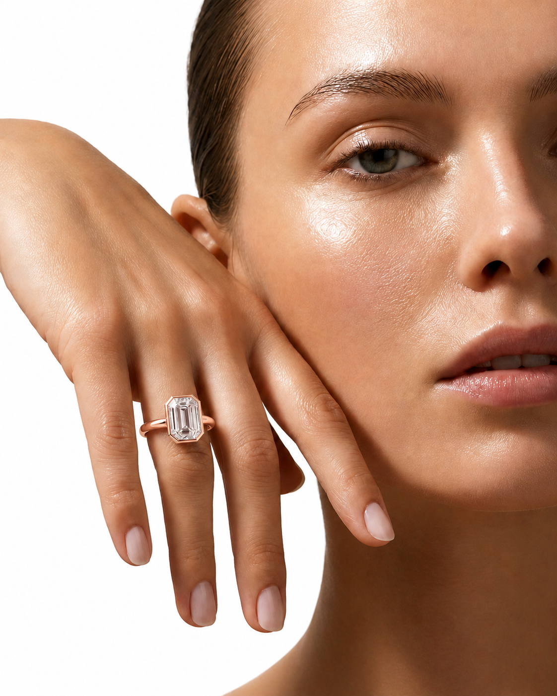 color_10K_RG, color_14K_RG &&A close-up lifestyle shot of a model wearing a rose gold ring with a large rectangular emerald-cut clear gemstone on her finger, set against a clean white background.