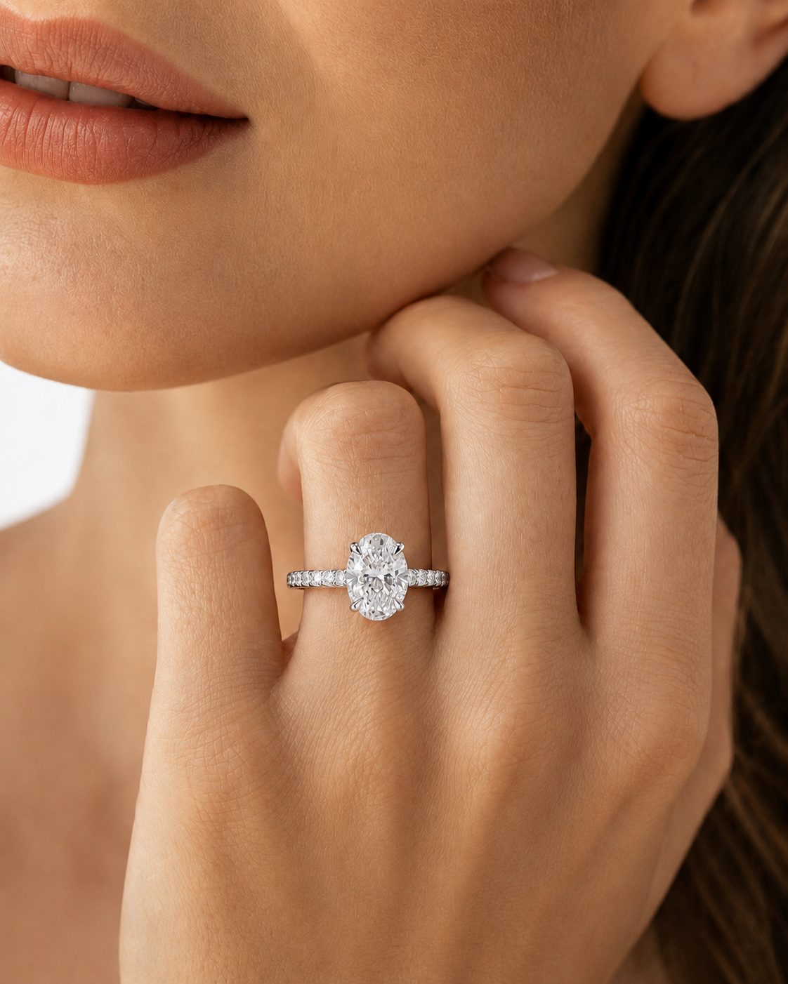 color_925_SIL,color_935_ARG,color_10K_WG, color_14K_WG &&A close-up lifestyle shot of a model wearing a silver-toned engagement ring with a round brilliant-cut center stone and a pavé band on her finger.
