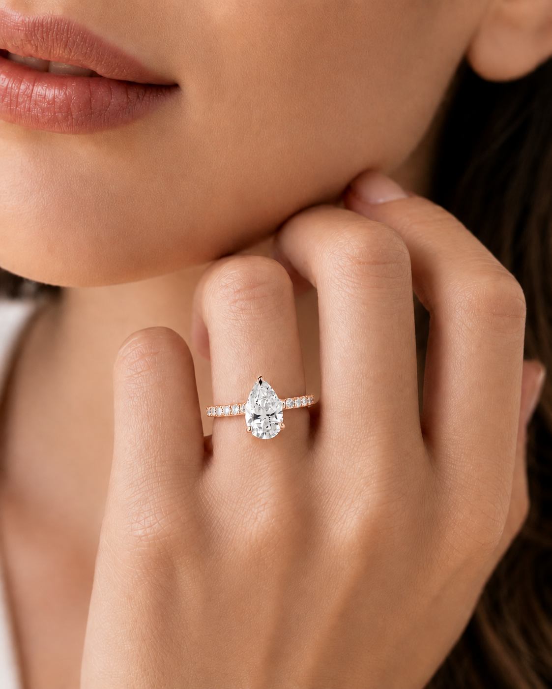 color_10K_RG, color_14K_RG &&A close-up lifestyle shot of a model wearing a pear-cut diamond ring on a slim pavé band.