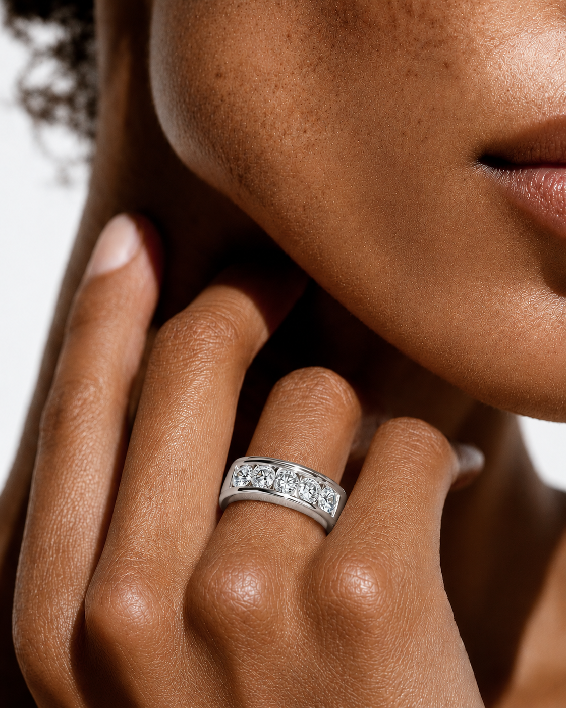 color_925_SIL,color_935_ARG,color_10K_WG, color_14K_WG &&A close-up lifestyle shot of a model wearing a silver band ring set with round clear gemstones on her finger.