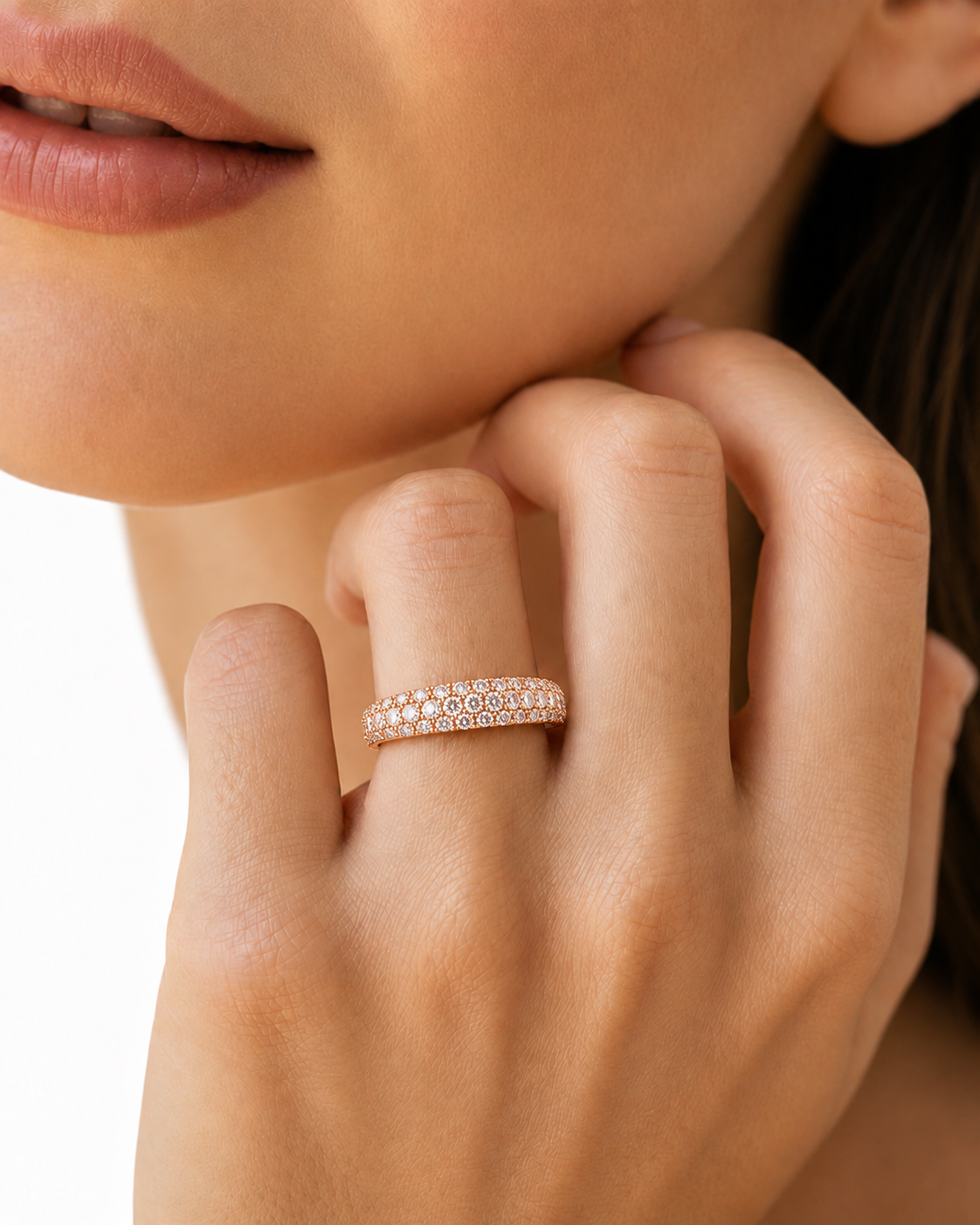 color_10K_RG, color_14K_RG &&A close-up of a woman's hand wearing a rose gold eternity ring set with small clear stones, against a clean white background.