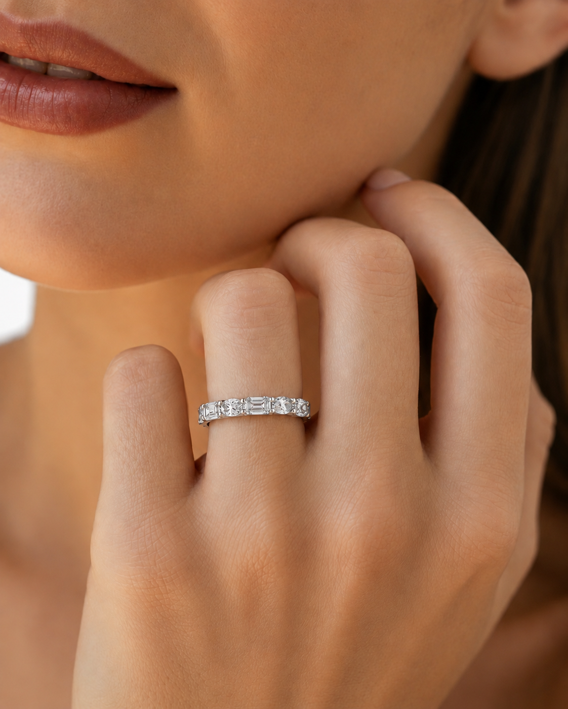 color_925_SIL,color_935_ARG,color_10K_WG, color_14K_WG &&A close-up lifestyle shot of a woman wearing a silver band ring with a row of small rectangular-cut clear stones on her ring finger.