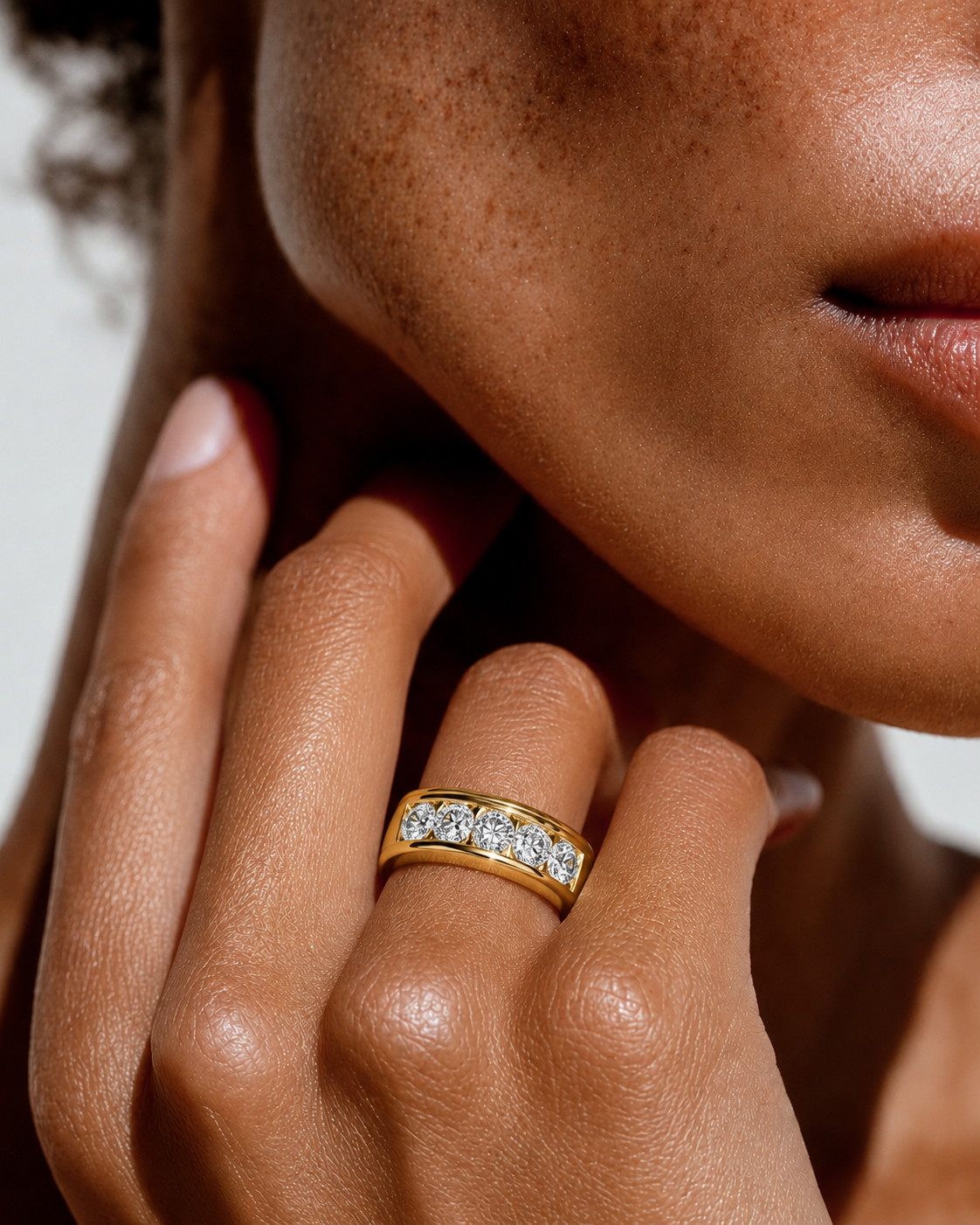 color_10K_YG, color_14K_YG &&A close-up lifestyle shot of a model wearing a yellow gold eternity ring set with round brilliant-cut diamonds on her finger.