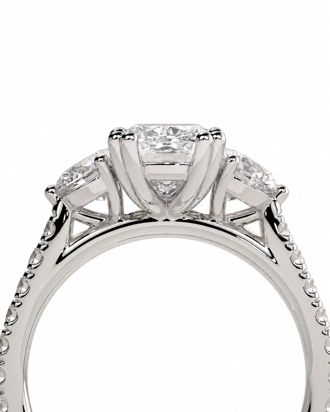 color_925_SIL,color_935_ARG,color_10K_WG, color_14K_WG &&A close-up shot of a silver-toned diamond engagement ring with a central round brilliant-cut diamond flanked by two smaller round diamonds on a white background.