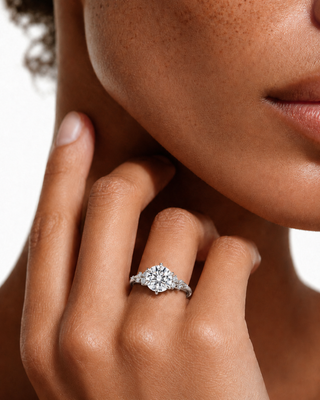 color_925_SIL,color_935_ARG,color_10K_WG, color_14K_WG &&A close-up lifestyle shot of a woman's hand and lower face wearing a diamond engagement ring with a marquise-cut center stone and diamond accents on a silver-toned band.