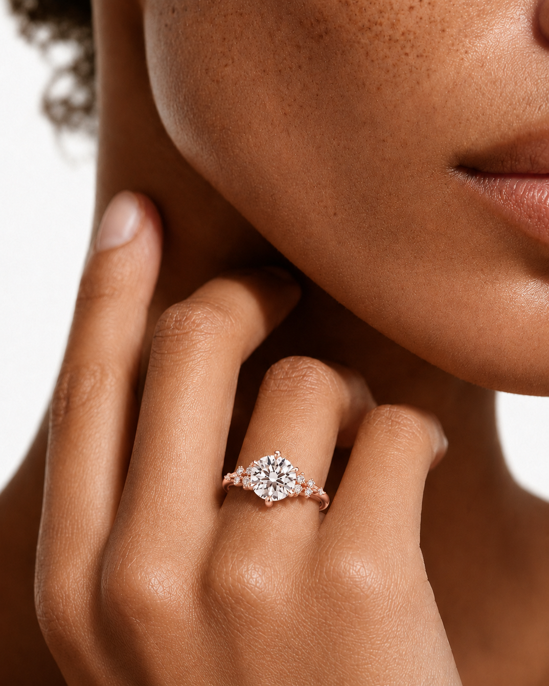 color_10K_RG, color_14K_RG &&A close-up lifestyle shot of a model wearing a rose gold ring with a round-cut diamond cluster and marquise-cut side diamonds on her finger.