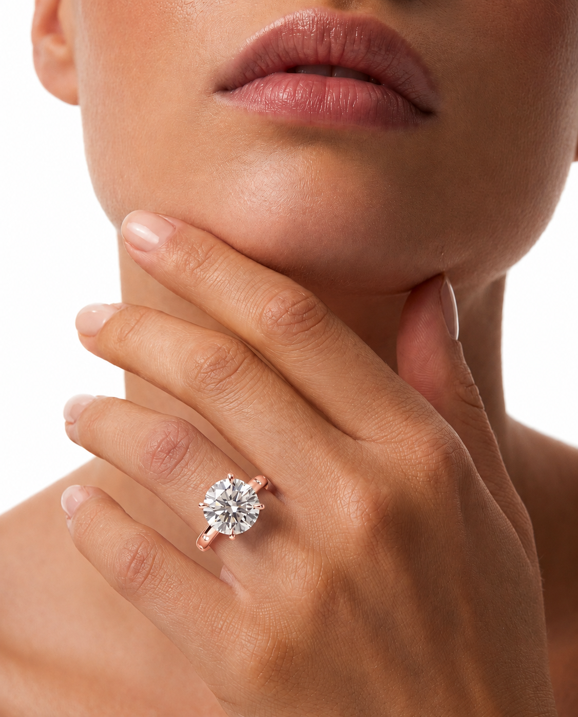 color_10K_RG, color_14K_RG &&A close-up lifestyle shot of a model wearing a rose gold engagement ring with a round brilliant-cut diamond. The model's hand, chin, and lower face are visible against a clean white background.