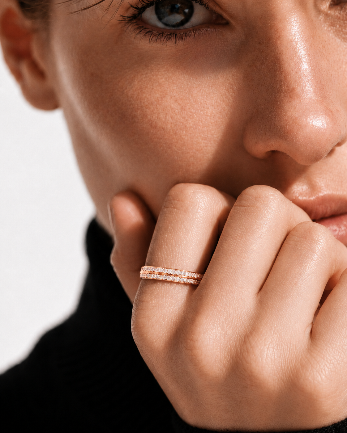 color_10K_RG, color_14K_RG &&A close-up lifestyle shot of a model wearing a delicate double-row rose gold ring set with small clear stones on her finger, against a clean white background.