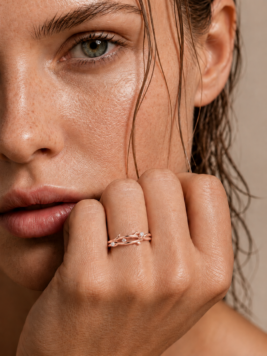 color_10K_RG, color_14K_RG &&A close-up lifestyle shot of a woman wearing a delicate gold ring with small clear stones on her finger, with her hand resting near her chin against a soft beige background.