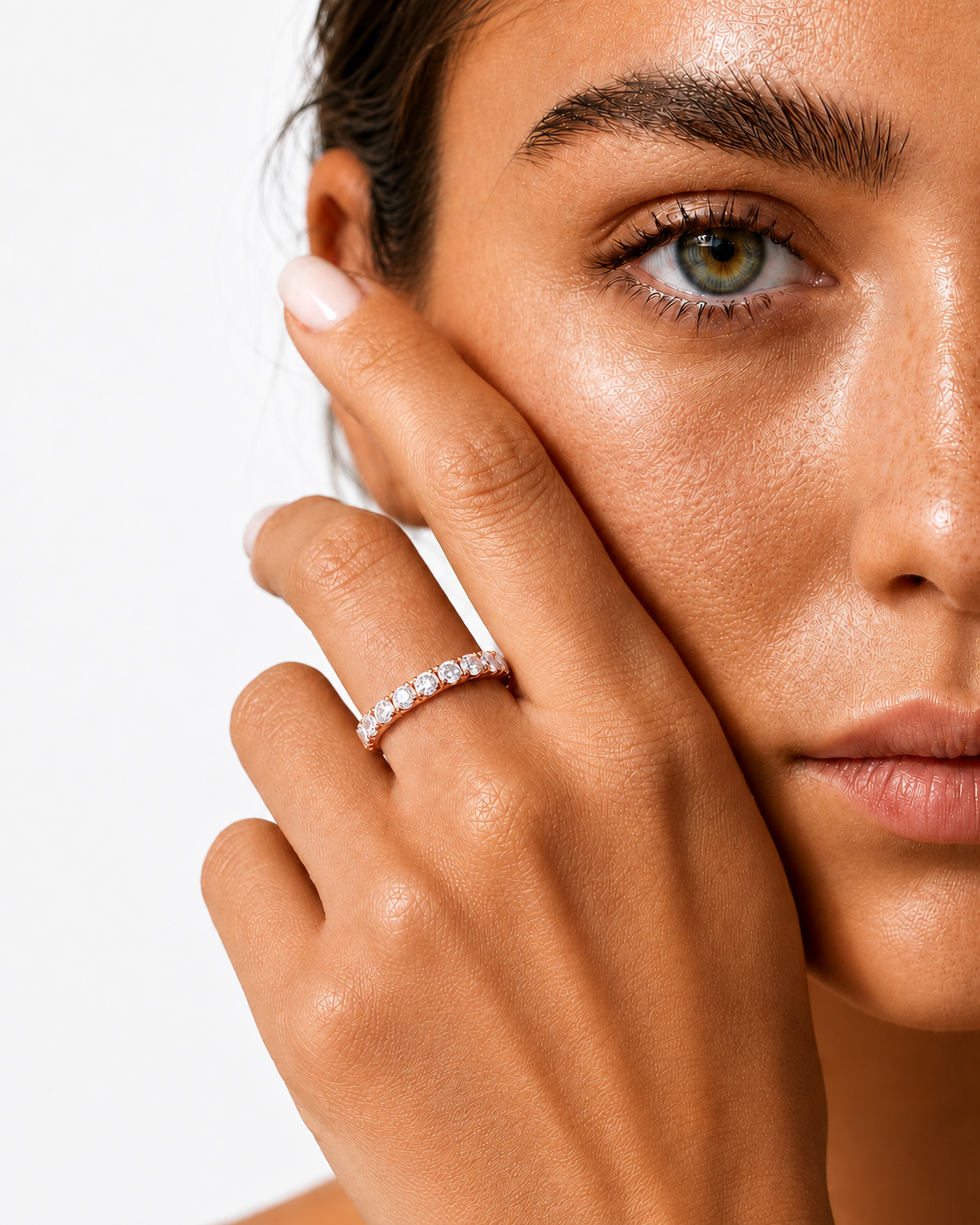 color_10K_RG, color_14K_RG &&A close-up lifestyle shot of a woman wearing a sparkling diamond engagement ring on her finger, with her hand resting against her cheek against a clean white background.