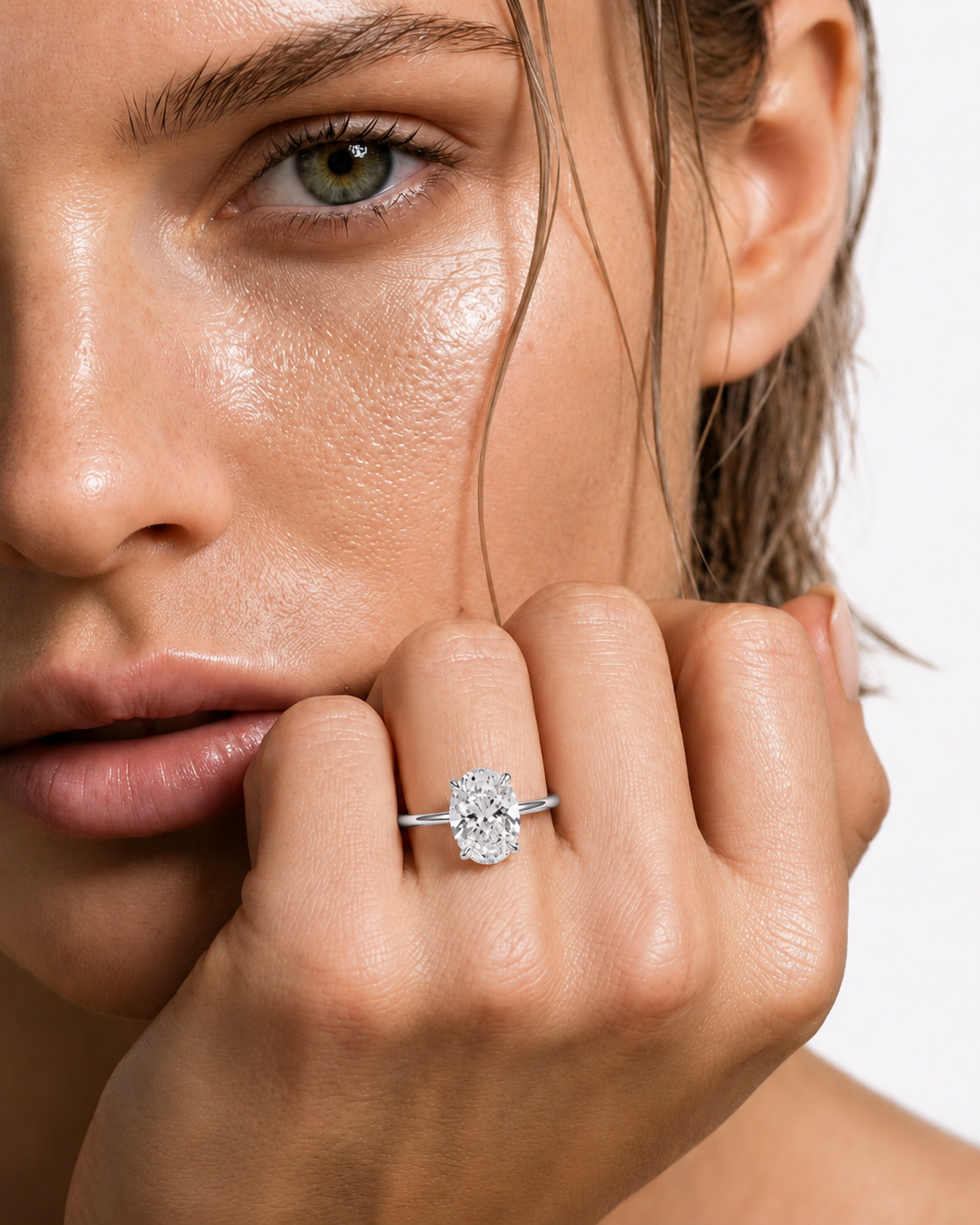 color_925_SIL,color_935_ARG,color_10K_WG, color_14K_WG &&A close-up lifestyle shot of a model wearing a silver engagement ring with a round-cut clear gemstone on her finger.