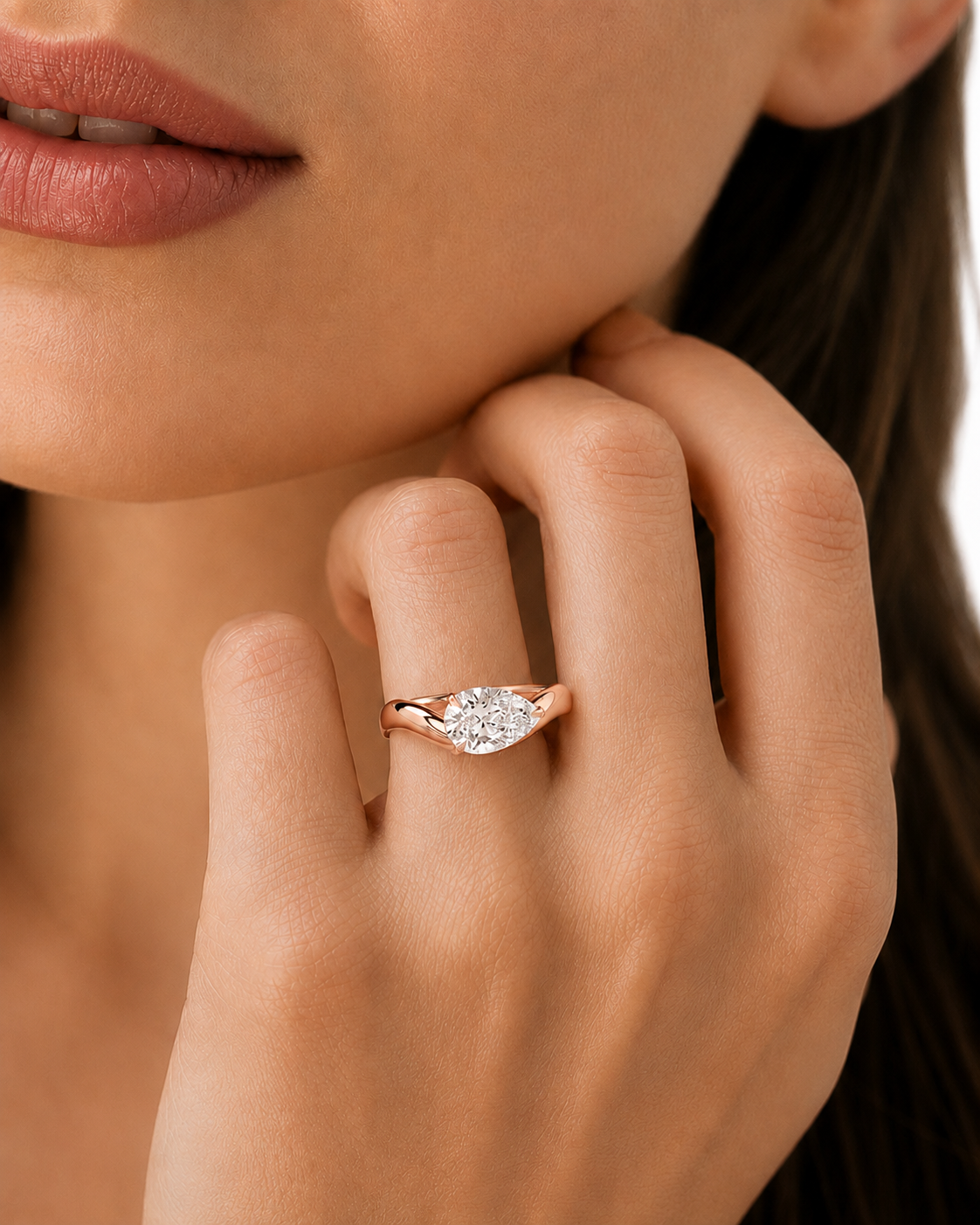 color_10K_RG, color_14K_RG &&A close-up lifestyle shot of a woman wearing a rose gold ring with a marquise-cut diamond on her finger. The ring is shown on her hand, with her lips and hair visible in the background.