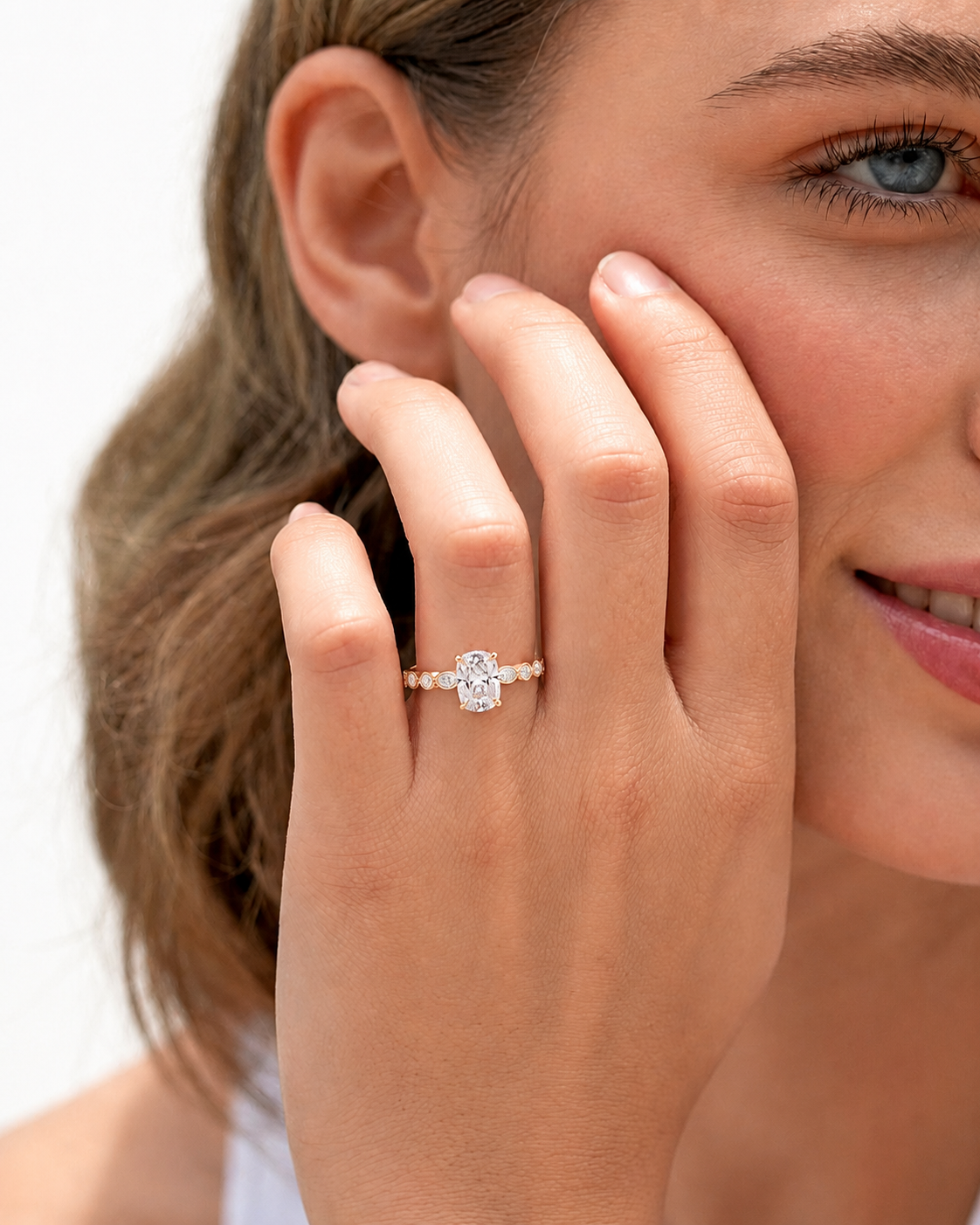color_10K_RG, color_14K_RG &&
A close-up lifestyle shot of a woman wearing a silver ring with a central clear gemstone and a delicate pearl beadline, resting on her ring finger.