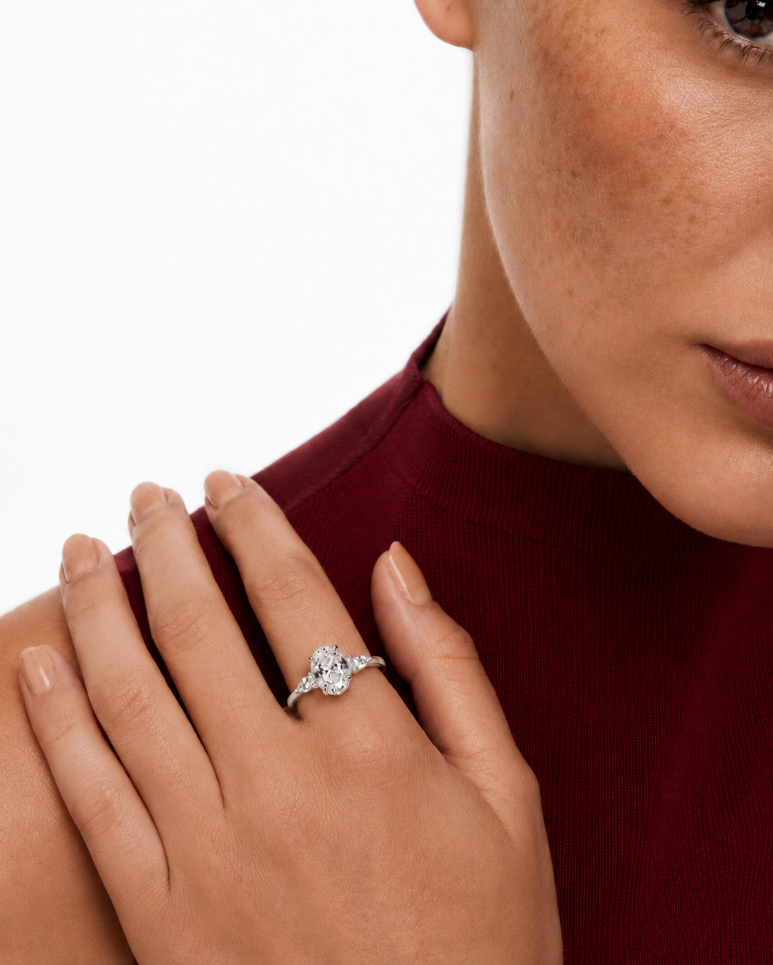 color_925_SIL,color_935_ARG,color_10K_WG, color_14K_WG &&A close-up of a woman's hand wearing a silver-toned diamond ring with a floral cluster centerstone, set against a white background and a dark red ribbed top.