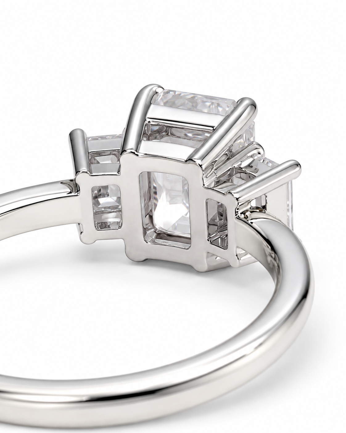 color_925_SIL,color_935_ARG,color_10K_WG, color_14K_WG &&A close-up studio shot of a silver-toned ring featuring a central rectangular clear gemstone surrounded by smaller side stones, set in a polished metal band on a white background.