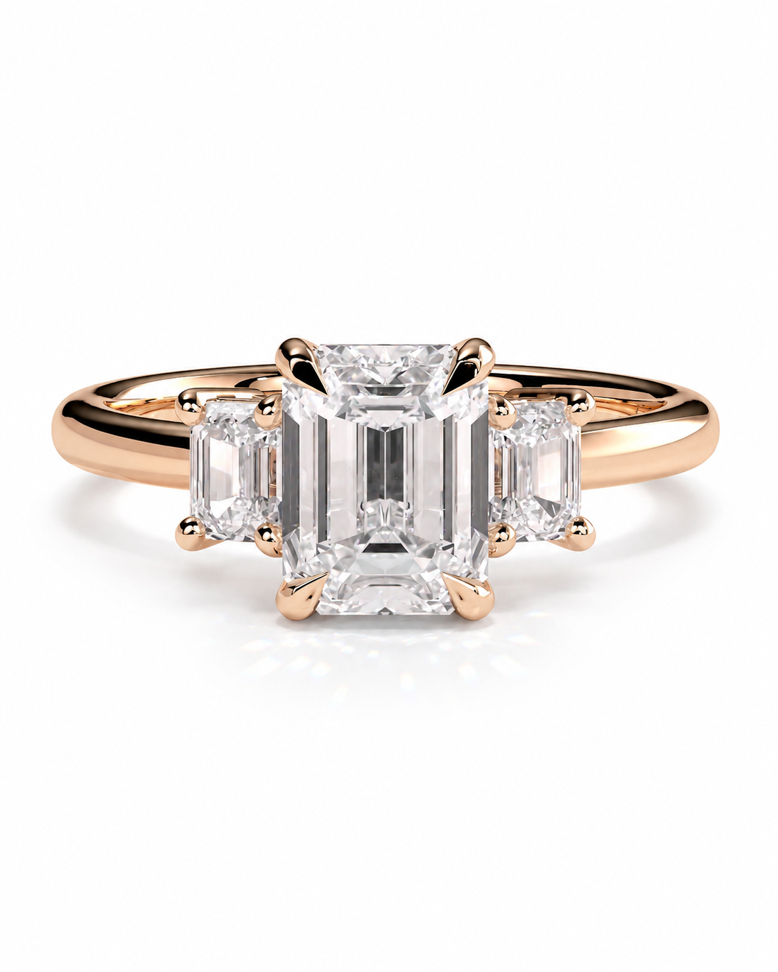 color_10K_RG, color_14K_RG &&A rose gold three-stone engagement ring featuring a large emerald-cut center diamond flanked by two smaller emerald-cut side diamonds, set against a clean white background.