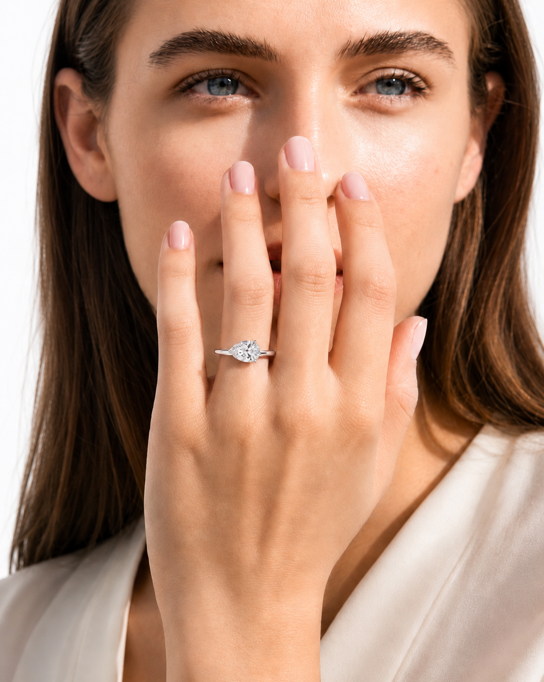 color_925_SIL,color_935_ARG,color_10K_WG, color_14K_WG &&A close-up lifestyle shot of a woman wearing a delicate silver ring with a marquise-cut diamond on her finger, holding her hand near her face against a clean white background.