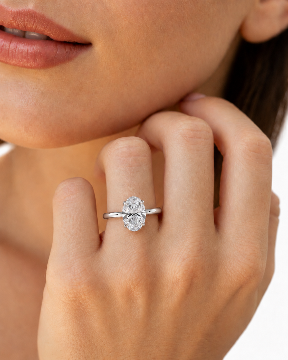 color_925_SIL,color_935_ARG,color_10K_WG, color_14K_WG &&A close-up lifestyle shot of a woman's hand wearing a silver oval solitaire engagement ring with a clear round-cut diamond. The ring is shown on her ring finger against a clean white background.