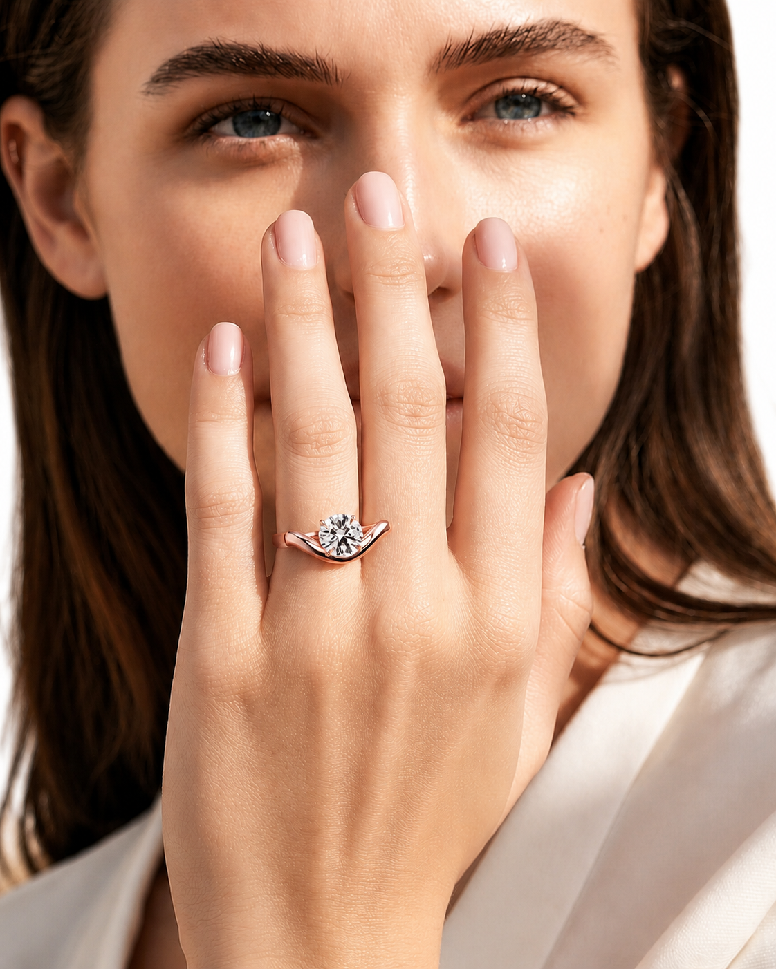 color_10K_RG, color_14K_RG &&A close-up lifestyle shot of a woman wearing a silver ring with a central clear gemstone on her finger, with her hand covering part of her face.