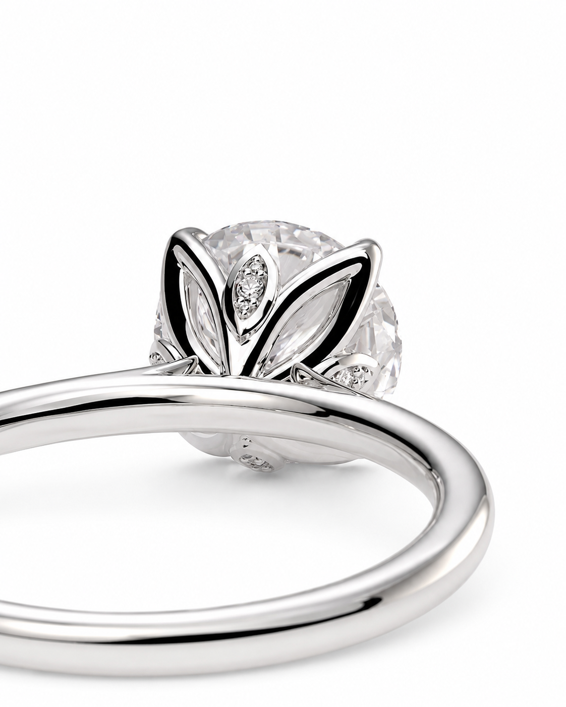 color_925_SIL,color_935_ARG,color_10K_WG, color_14K_WG &&A close-up studio shot of a silver-toned ring with a round clear gemstone in a leaf-like setting with small marquise-cut accent stones, on a white background.
