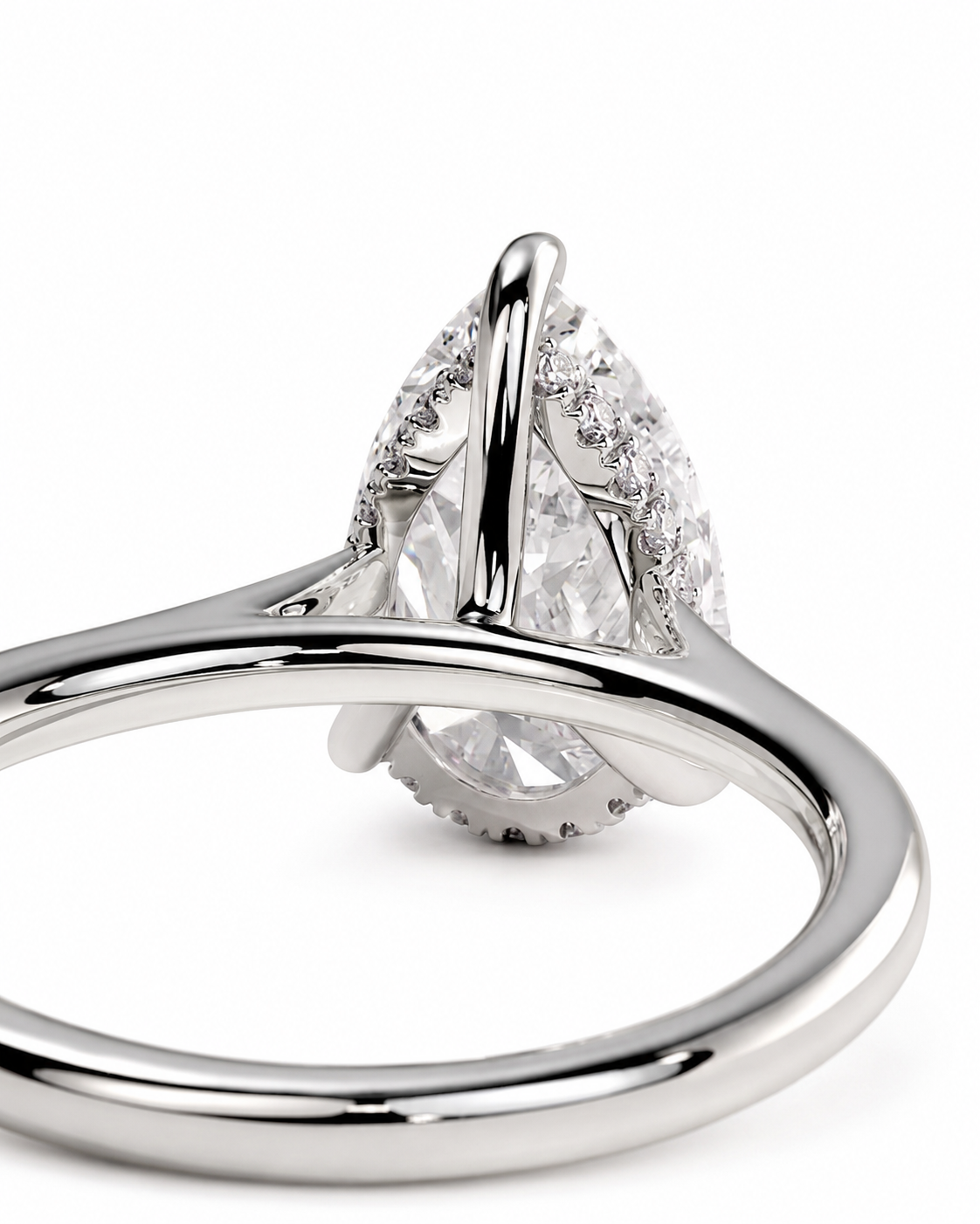 color_925_SIL,color_935_ARG,color_10K_WG, color_14K_WG &&A close-up shot of a silver-toned ring featuring a pear-cut clear gemstone in a prong setting with small accent diamonds, shown on a clean white background.