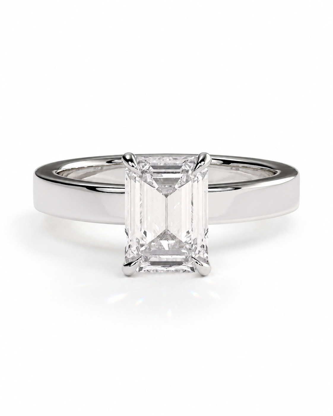 color_925_SIL,color_935_ARG,color_10K_WG, color_14K_WG &&An emerald-cut diamond solitaire engagement ring set in a polished silver-colored band, shown against a seamless white background.