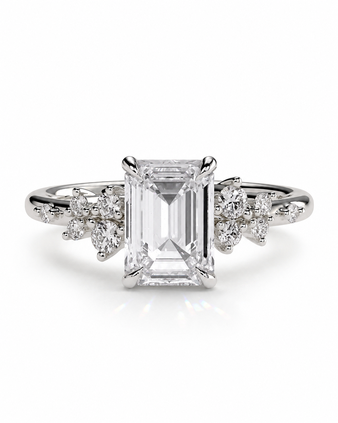 color_925_SIL,color_935_ARG,color_10K_WG, color_14K_WG &&An emerald-cut diamond engagement ring with a silver-toned band and small accent diamonds on either side, shown on a clean white background.