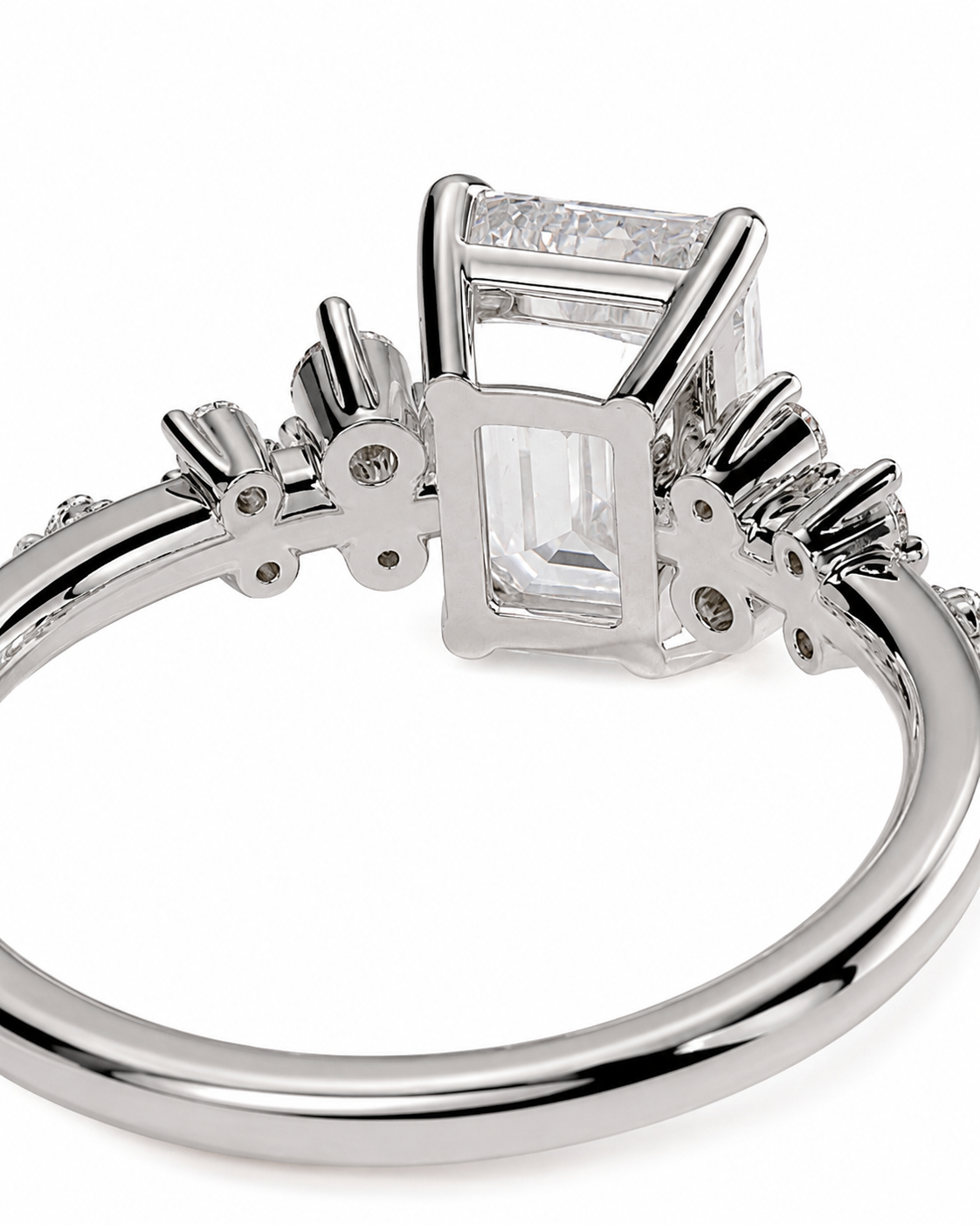 color_925_SIL,color_935_ARG,color_10K_WG, color_14K_WG &&A close-up shot of a silver-toned ring featuring a rectangular baguette-cut clear gemstone in a prong setting, with smaller accent stones along the band, on a white background.