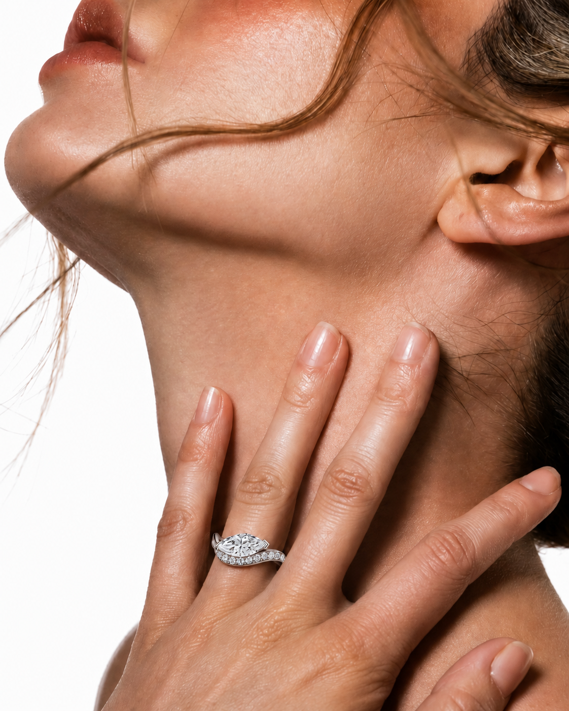 color_925_SIL,color_935_ARG,color_10K_WG, color_14K_WG &&A close-up lifestyle shot of a woman's neck and hand, wearing a sparkling silver-toned ring with clear gemstones on her ring finger against a white background.