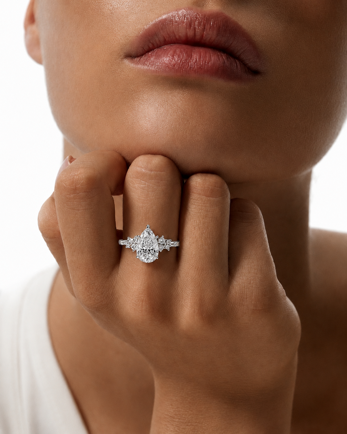 color_925_SIL,color_935_ARG,color_10K_WG, color_14K_WG &&A close-up lifestyle shot of a model wearing a silver diamond ring on her finger, with her hand resting on her chin against a clean white background.